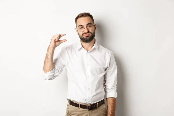 Empreendedor masculino decepcionado mostrando pequeno objeto e suspiros, de pé sobre fundo branco — Fotografia de Stock