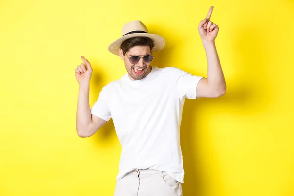 Koncepcja turystyki, podróży i wakacji. mężczyzna turysta korzystających wakacje, taniec w słomkowym kapeluszu i okulary, wskazując palce bokiem — Zdjęcie stockowe