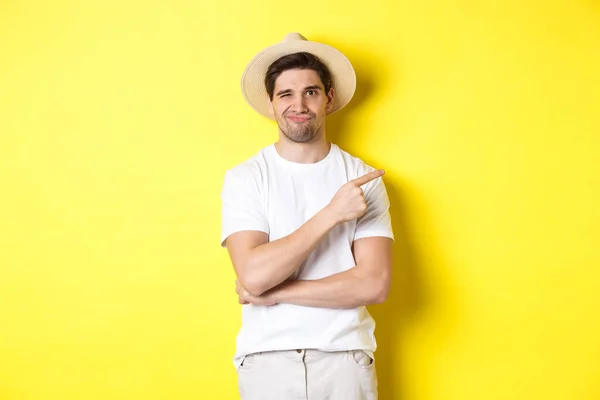 Escéptico turista masculino quejándose, señalando con el dedo a algo malo o cojo, de pie sin distraerse contra el fondo amarillo — Foto de Stock