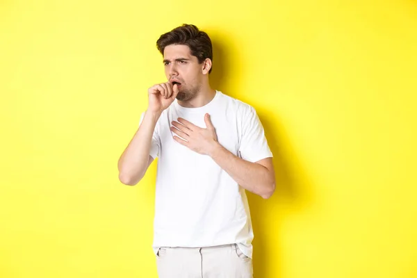 咳や気分が悪く黄色の背景の上に立って、 covid-19やインフルエンザの症状を持つ人のイメージ — ストック写真