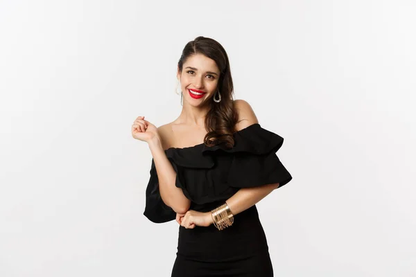 Moda e beleza. Mulher comemorando e dançando em vestido preto, se divertindo e sorrindo, de pé sobre fundo branco — Fotografia de Stock