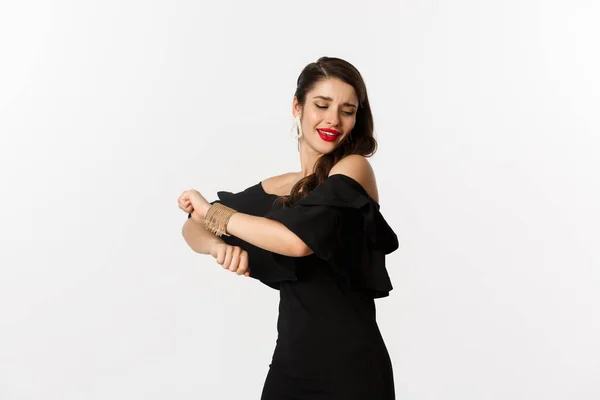 Moda y belleza. Atractiva mujer sintiéndose feliz y bailando en vestido de fiesta negro, de pie despreocupado sobre fondo blanco — Foto de Stock