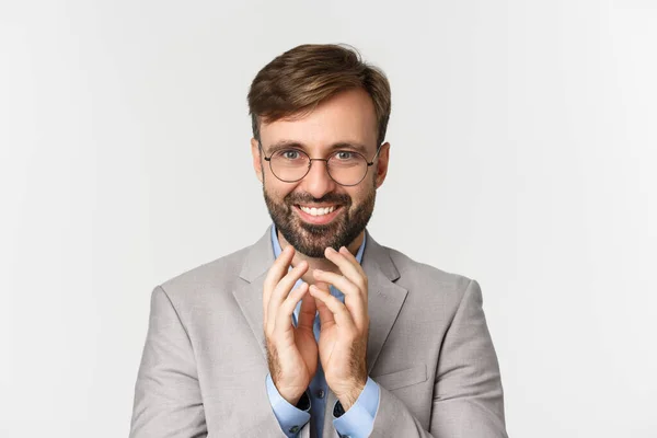 Close-up de empresário barbudo em óculos e terno, planejando algo, sorrindo tortuoso e tendo plano perfeito, em pé sobre fundo branco — Fotografia de Stock