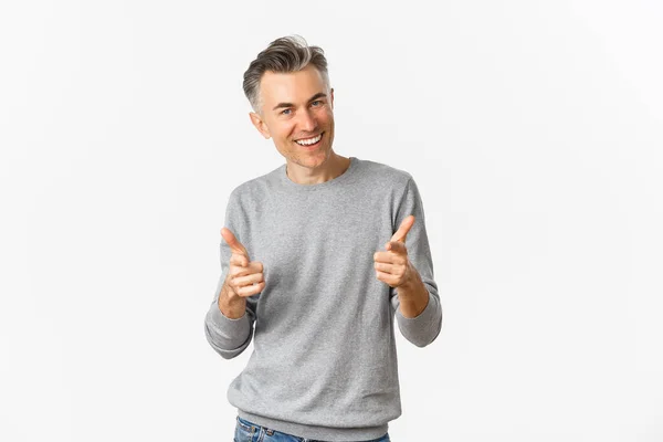 Hombre de mediana edad descarado con un peinado corto gris, señalando con los dedos a la cámara y sonriendo, alabando el buen trabajo o felicitando, de pie sobre fondo blanco —  Fotos de Stock