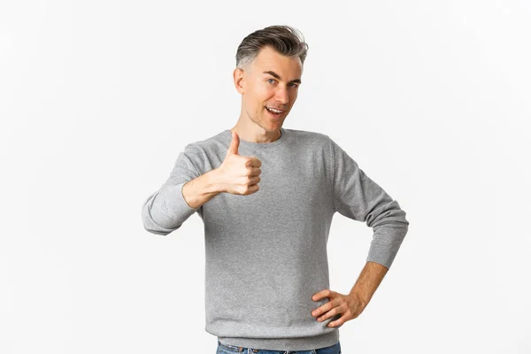 Retrato de homem de meia-idade orgulhoso e feliz, sorrindo satisfeito e mostrando polegares para cima, louvar algo bom, de pé sobre fundo branco — Fotografia de Stock