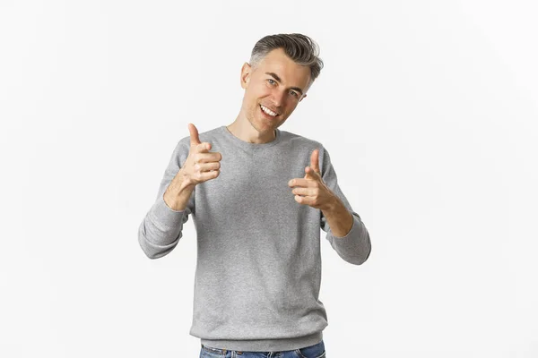Retrato de homem de meia-idade bonito e confiante, mostrando polegares para cima e sorrindo satisfeito, aprovar e como algo bom, de pé sobre fundo branco — Fotografia de Stock
