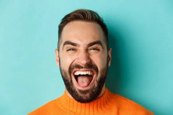 Tiro de cabeça de homem feliz e despreocupado com a barba, rindo e olhando para a câmera, de pé em suéter laranja — Fotografia de Stock