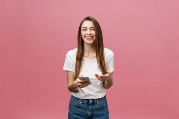 Fotografie veselý roztomilý krásná mladá žena chatování mobilním telefonem izolované přes růžové stěny pozadí. — Stock fotografie
