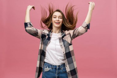 Yaşam tarzı kavramı. Pembe arka planda müzik dinlemek için telefonu kullanan genç bir kadın.