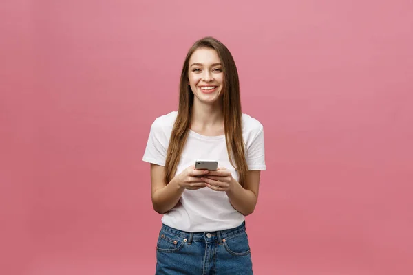 Foto av glad söt vacker ung kvinna chatta med mobiltelefon isolerad över rosa vägg bakgrund. — Stockfoto