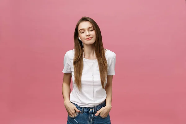 Lifestyle concept. Jonge vrouw met behulp van telefoon voor het luisteren naar muziek op roze achtergrond — Stockfoto