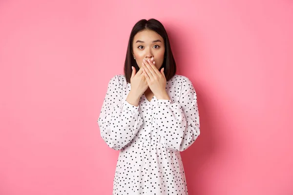 Kép meglepett ázsiai női modell zihálás, fedél száj és nézi a kamera, álló csodálkozva szemben rózsaszín háttér — Stock Fotó