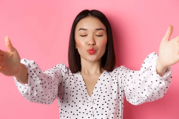 Gros plan de belle femme asiatique beauté blogueur, lèvres pucker et les yeux fermés pour baiser, prendre selfie, debout sur fond rose — Photo
