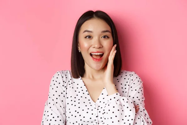 Primer plano de hermosa mujer asiática llamando para usted, haciendo anuncio o gritando, de pie sobre fondo rosa — Foto de Stock