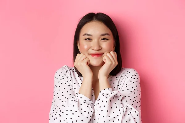 Bellezza e stile di vita. Primo piano di adorabile donna asiatica che mostra le guance gonfie, sorridente e guardando felice, in piedi su sfondo rosa — Foto Stock