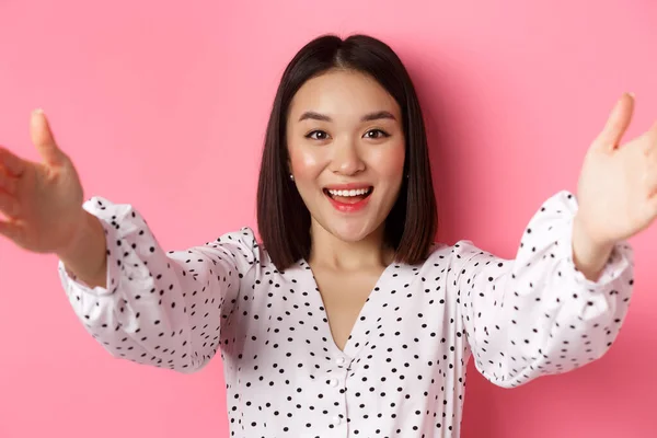 Primer plano de lindo asiático mujer llegar manos hacia adelante, tomando selfie, registro belleza blog y sonriendo, de pie sobre rosa fondo —  Fotos de Stock
