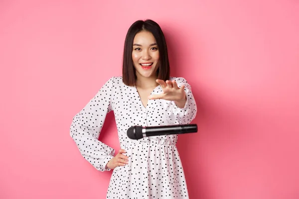 Happy asian woman drop the microphone, smiling and looking confident at camera, standing over pink background — Stock Photo, Image