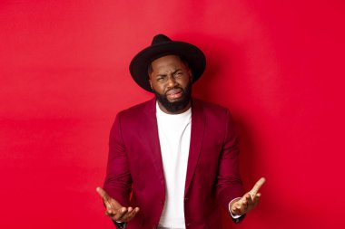 Hüsrana uğramış ve sefil Afro-Amerikan adam mızmızlanıyor, hayattan şikayet ediyor ve ağlıyor, bir şey için yalvarıyor, kırmızı arka planda duruyor.