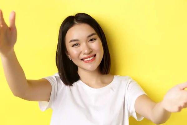 Primer plano de la chica asiática moderna tomando selfie en el teléfono inteligente, cámara móvil vista de la mujer bonita sonriendo, de pie sobre el fondo amarillo — Foto de Stock