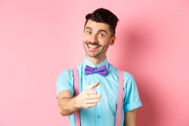 Tanıştığıma memnun oldum. Yakışıklı genç adam el sıkışmak için elini uzattı, gülümsedi arkadaşça ve kibarca, kendini tanıttı, pembe arka planda duruyordu.