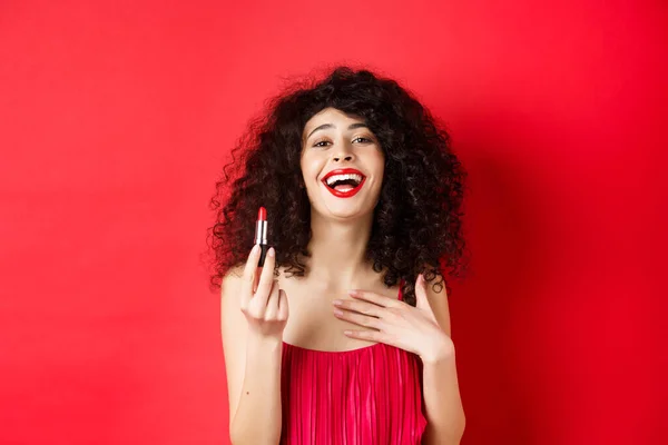 Elegante vrouw in jurk, met rode lippenstift en lachen, staande over studio achtergrond — Stockfoto