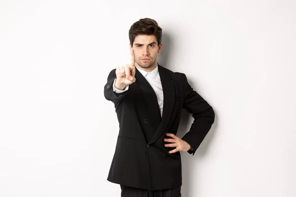 Portrait of serious handsome man in business suit, showing one finger to prohibit or decline something, telling to stop, disagree with you, standing over white background — Stock Photo, Image