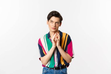 Sinsi genç adamın bir planı var. Çan kulesi gibi parmakları var ve sol üst köşede kurnaz görünüyor. Bir şeyler planlıyor, beyaz arka planda duruyor.