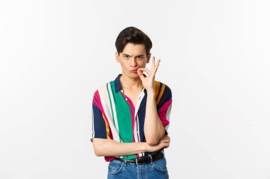 Surat asan adam fermuarlı ağız, umut dolu dudaklar, ciddi görünüyor, beyaz arka planda duruyor.