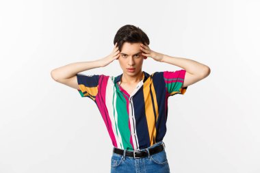 Arsız çift cinsiyetli adam kameraya bakıyor, delici bakışlarla sana bakıyor, beyaz arka planda duruyor.