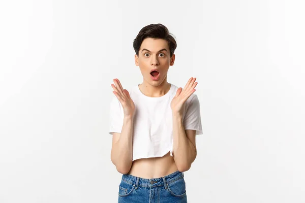 Lgbtq e concetto di orgoglio. Immagine di ragazzo queer sorpreso applaudire le mani e guardando in soggezione la fotocamera, in piedi in crop top sullo sfondo bianco — Foto Stock