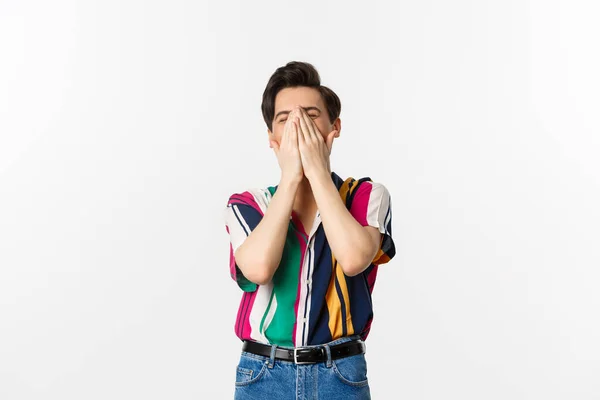 Image of young stylish man sneezing in hands, standing over white background — Stock Photo, Image