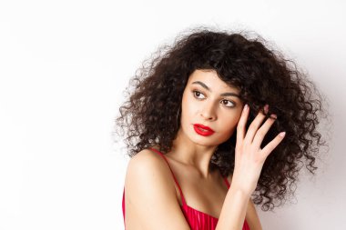 Şefkatli romantik bir kadının yakın çekimi, nazikçe yüzüne dokunması ve şehvetli görünmesi, beyaz arka plan.