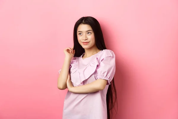 Güzel Asyalı kadın gülümsüyor ve yan bakıyor, pembe romantik arka planda giyinmiş duruyor. — Stok fotoğraf