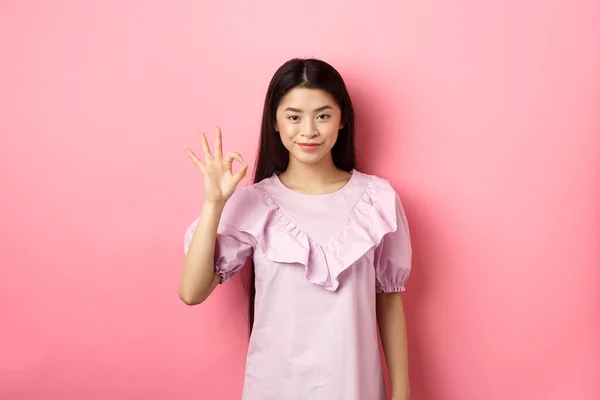 Sonriente mujer asiática en vestido mostrando signo bien, alabanza y elogio buena cosa, aprobar excelente opción, de pie sobre fondo rosa —  Fotos de Stock