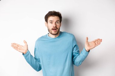 - İnanılmaz. İnançsızlıkla bakan, ellerini yana açmış, etkilenmiş, beyaz arka planda duran genç adam.