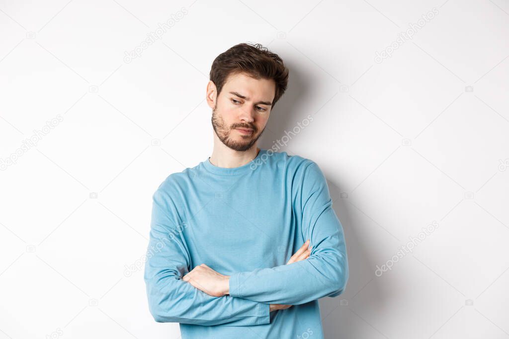 Indecisive and thoughtful bearded man thinking, looking down pensive and making choice, standing over white background