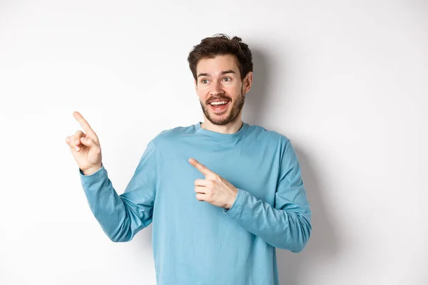 Homme barbu excité vérifier offre spéciale, pointant et regardant la publicité avec le visage heureux, debout sur fond blanc — Photo