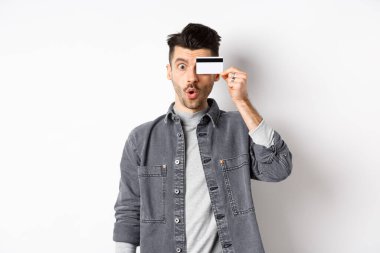 Heyecanlı komik adam plastik kredi kartını gözünün içine aldı ve 