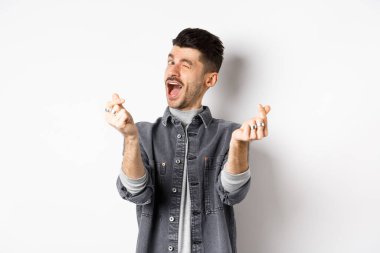 Komik adam göz kırpıyor, el işareti yapıyor, romantik ve mutlu hissediyor, beyaz arka planda duruyor.