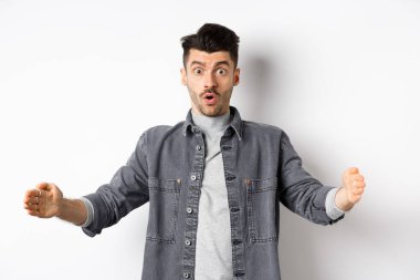 Büyük boyutlarda, büyük nesneleri şekillendiren, beyaz arka planda duran heyecanlı beyaz adam.