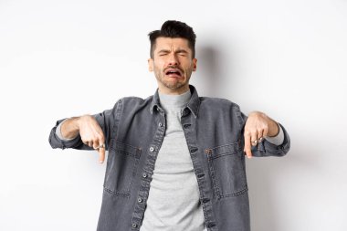 Üzgün, ağlayan, ağlayan, hıçkıra hıçkıra ağlayan, üzücü haberler veren, beyaz arka planda kot ceket giyen adam.