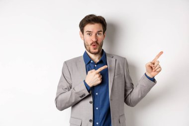 Heyecanlı, beyaz takım elbiseli beyaz iş adamı logoyu işaret ediyor, 