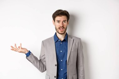 Yanlış olan ne? Takım elbiseli kafası karışık adam anlayamaz. Elleri havada, kameraya bakıyor, sorgulanıyor, beyaz arka planda duruyor.