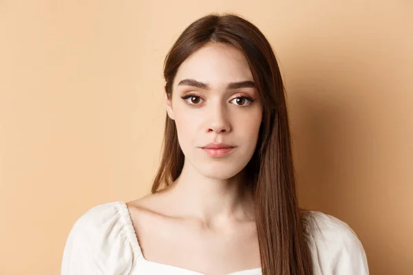 Close up of beautiful woman face with natural makeup and relaxed expression, standing on beige background — 스톡 사진