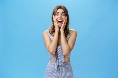 Karizmatik bakışları, güzel dişleri olan güzel Avrupalı bir kadının şaşkınlık ve neşe dolu bakışları kameraya hayran kalarak ve hayran kalarak geniş bir şekilde ellerini yanaklarına bastırarak gülümsemesine şaşırdı.