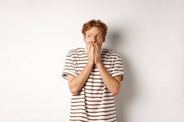 Şok olmuş kızıl saçlı, dedikoducu, kıkır kıkır gülen, soldan bakan, beyaz arka planda duran