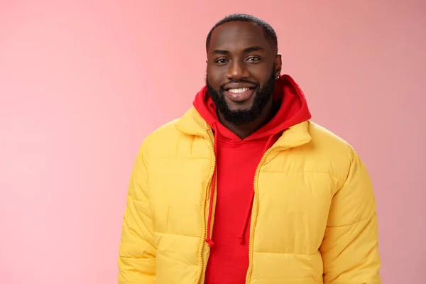 Waist-up happy charismatic good-looking bearded guy in yellow jacket red hoodie smiling joyfully white perfect smile talking have nice friendly conversation, standing pink background