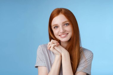 Şefkatli, samimi, genç, kızıl saçlı kız aşkı buldu. Sempati dolu, sevgi dolu, sevimli, gülümseyen, mutlu bakışlı kamera tutkusu. Güzel gülücük, mavi arka plan.