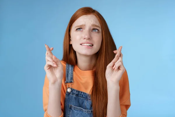 Worried unconfident young redhead intense cute girl frowning nervously waiting improtant moment cross fingers good luck bite lip anxiously frowning look upper left corner praying wish come true — Stock Photo, Image
