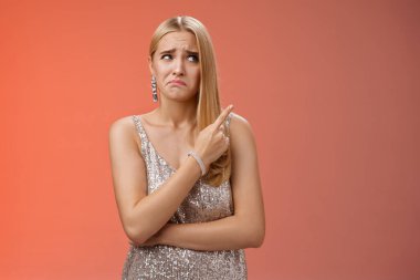Üzgün, kararsız, sevimli, sarışın, çekici, gümüşten gece elbisesi giymiş, utangaç, suratını asan, sağ üst köşeye bakan, şüpheli, belirsiz, kırmızı arka plan